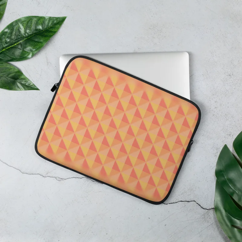 Warm Geometry Laptop Sleeve — tessellating triangles in coral red, golden yellow, and soft peach with a blurred vignette