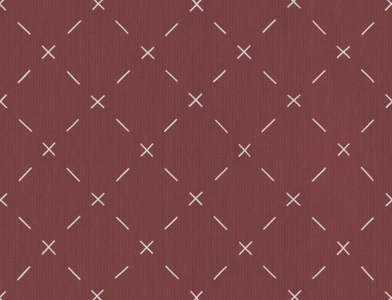Crimson Cross Stitch Laptop Sleeve design — repeating white cross and dash stitch motifs scattered across a rich burgundy
